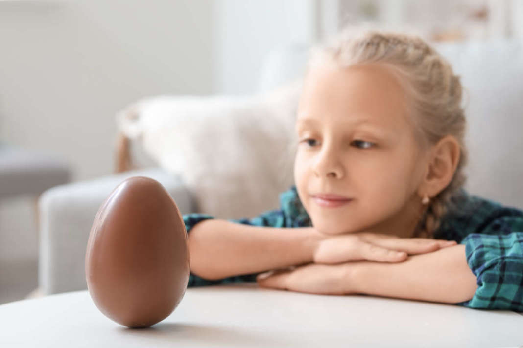 Bambina che guarda uovo di cioccolato