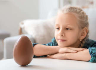Bambina che guarda uovo di cioccolato