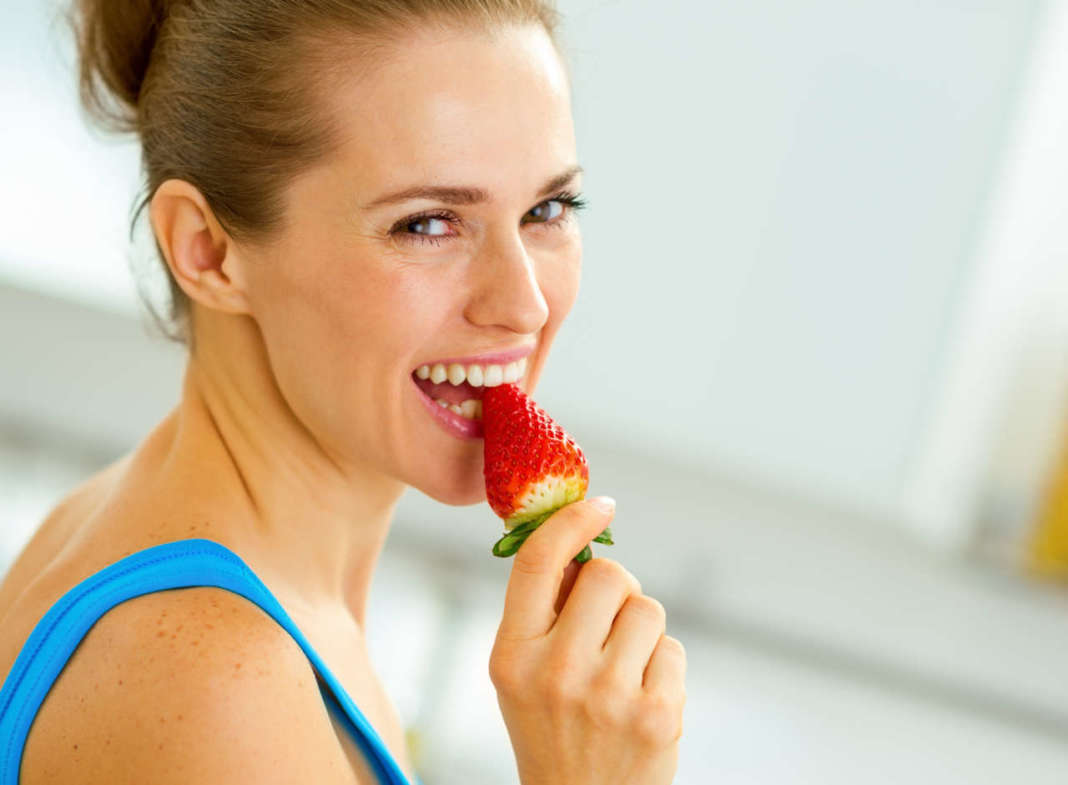 donna sorridente che mangia una fragola