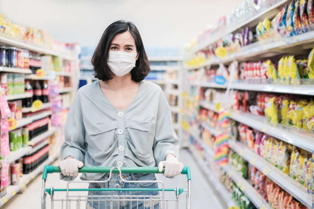 donna al supermercato con carrello, con maschera e guanti protettivi anti covid