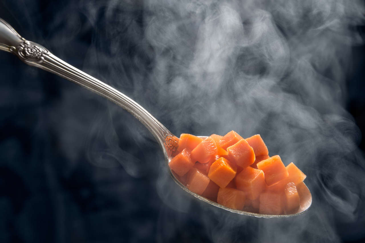 cucchiaio che contiene cubetti di carota cotti con la cucina a vapore